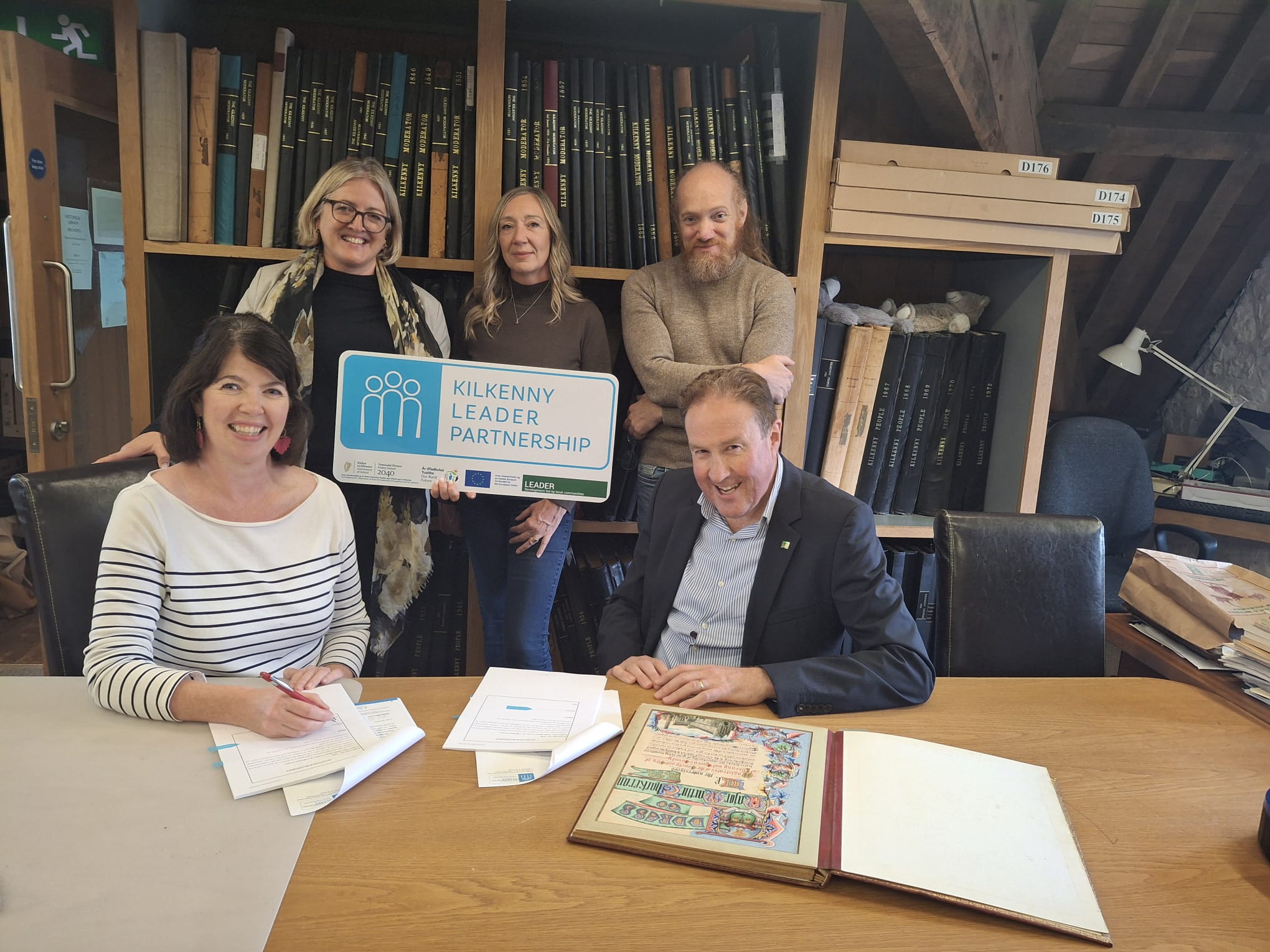 A professional photograph of Leader funding being awarded to Rothe House Trust. Five people are seated in the library of the Kilkenny Archaeological Society at Rothe House.